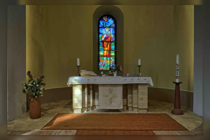 Innenraum der Dorfkirche Birkenwerder mit Blick auf Altar und farbiges Kirchenfenster.